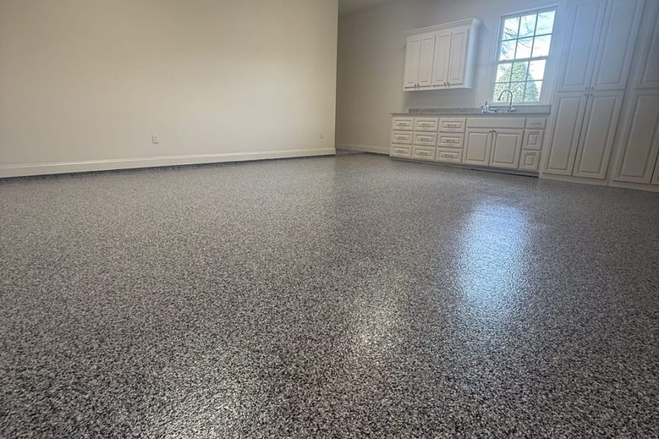Empty garage corner with a gray flake epoxy floor, window and overhead door opener