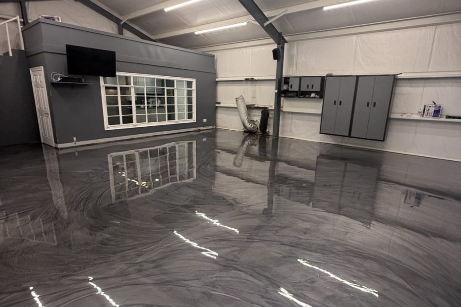 Silver gray metallic epoxy floor in a metal shop building with a glass door and mirror
