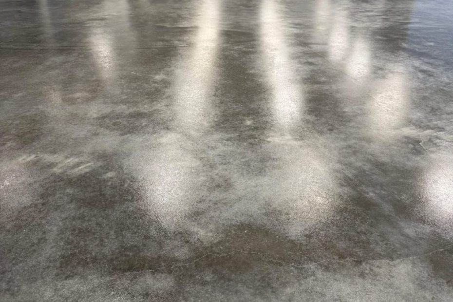 Smooth gray polished concrete floor with ceiling lights reflected in the surface