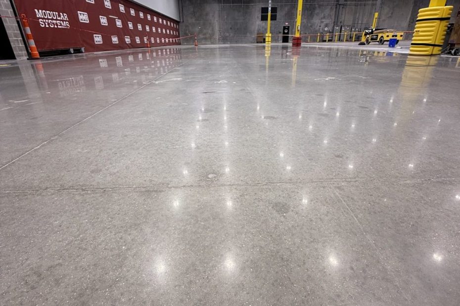 Polished concrete floor in a large warehouse with red block walls and light reflections